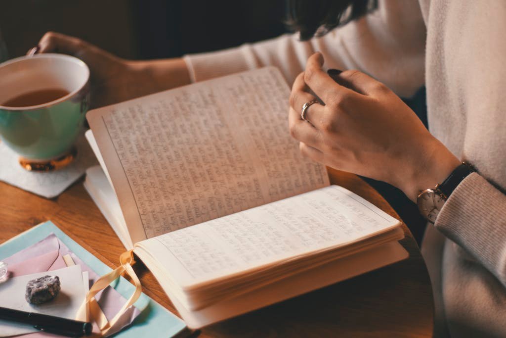 Open journal on a wooden table beside a cup of coffee, symbolizing quiet reflection and writing time.