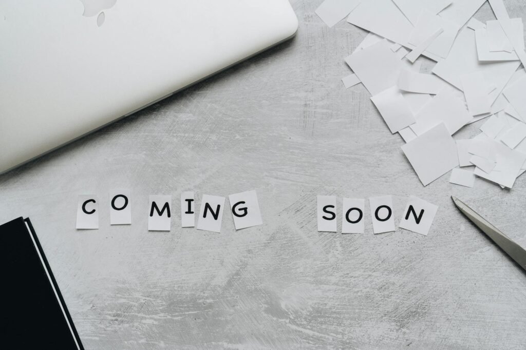 Paper squares spell out COMING SOON on a gray surface, with tools for learning nearby—welcoming midlife women to new possibilities.